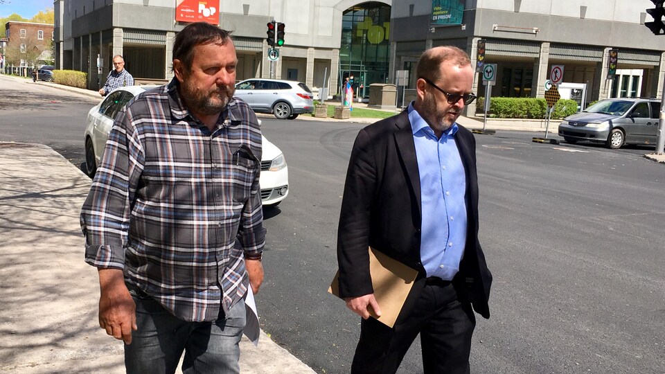 Deux hommes marchent sur un trottoir