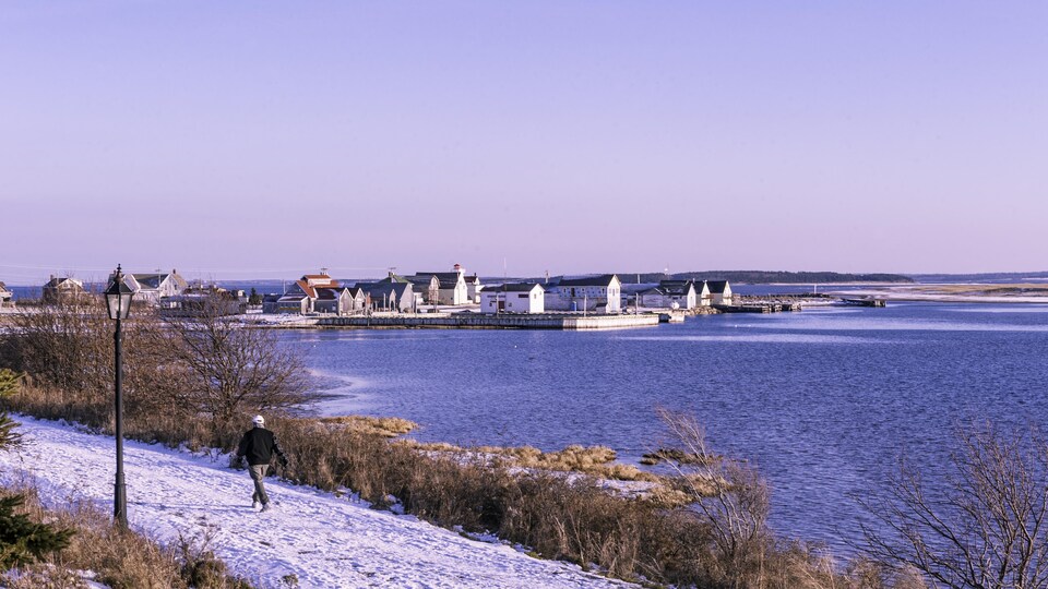 Un homme marche sur un sentier partiellement enneigé en décembre à l'Île-du-Prince-Édouard.