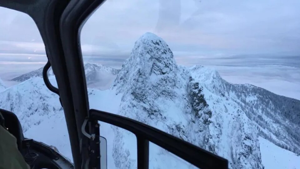 Une montagne enneigée vue du cockpit d'un hélicoptère.