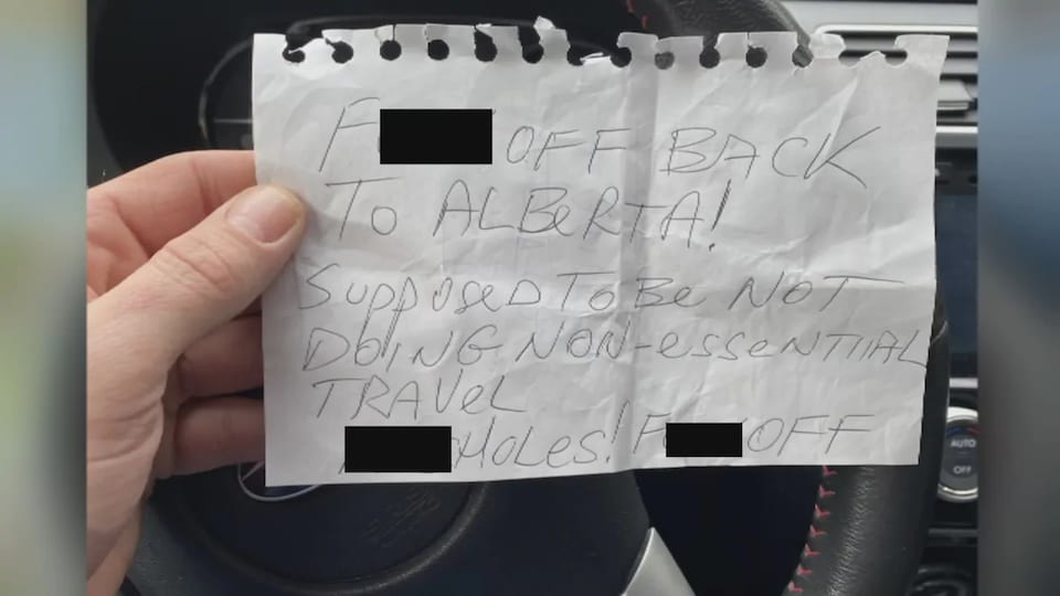 Un note où il est écrit en anglais Va te faire foutre! Retourne en Alberta! Tu n'es pas censé faire des voyages non essentiels.
