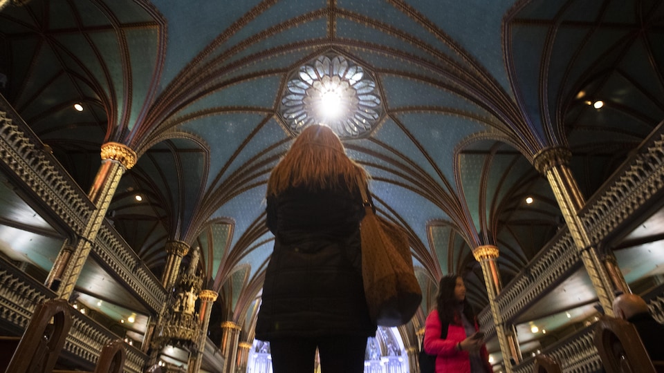 Une touriste dans l'allée centrale de la basilique Notre-Dame à Montréal.