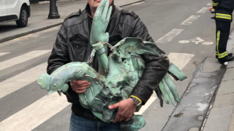 Un homme tient le coq, qui est visiblement cabossé.