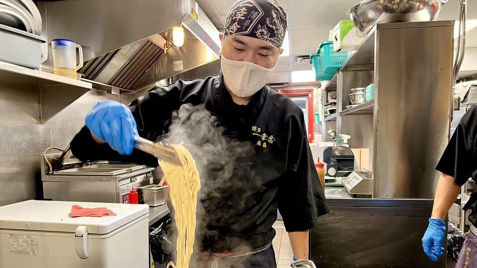 Un cuisinier prépare des nouilles ramen dans la cuisine du restaurant Ikkousha Ramen.
