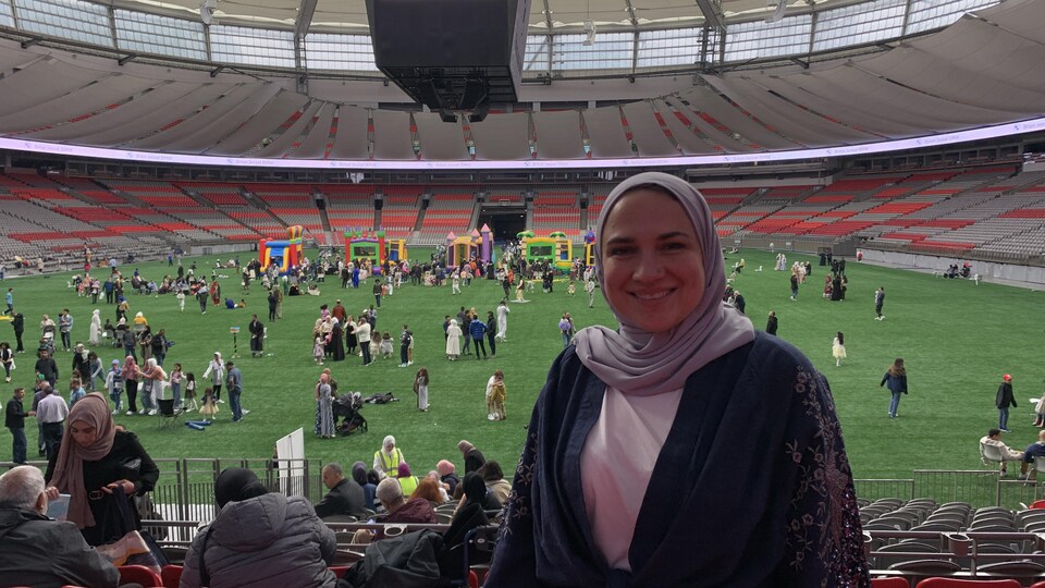 Une femme sourit dans l'enceinte d'un stade.
