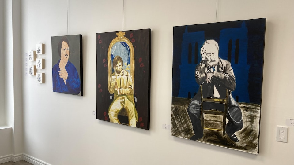 Trois tableaux accrochés sur un mur.