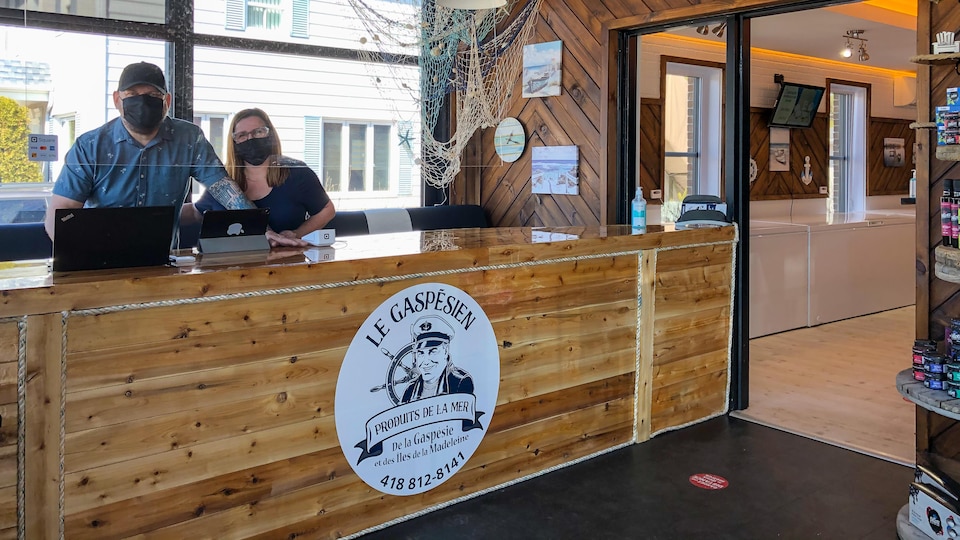 Deux employés de la poissonnerie Le Gaspésien derrière le comptoir à l'accueil.