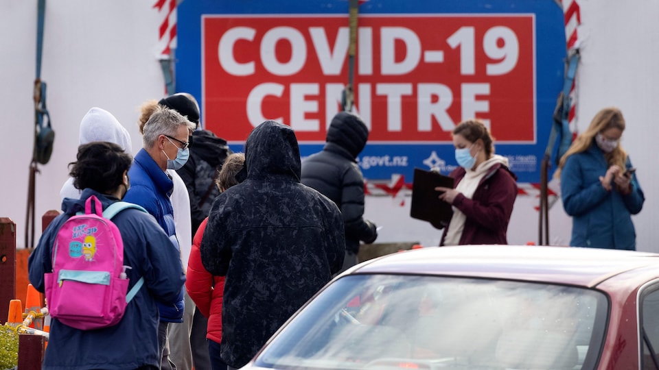 Un groupe de femmes et d'hommes devant un centre de dépistage de la COVID-19