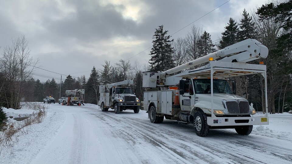 Des camions de Nova Scotia Power stationnés le long d'une route secondaire.