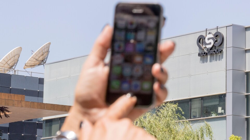 Une femme appuie sur le bouton d'un téléphone intelligent devant un immeuble.
