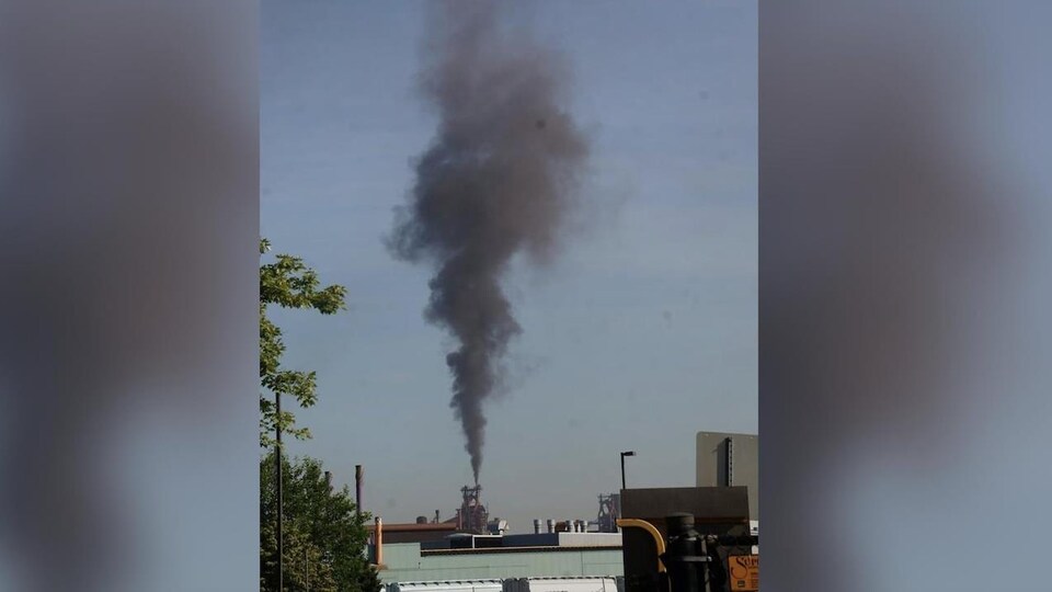 Un nuage de fumée s'échappe d'une cheminée au loin
