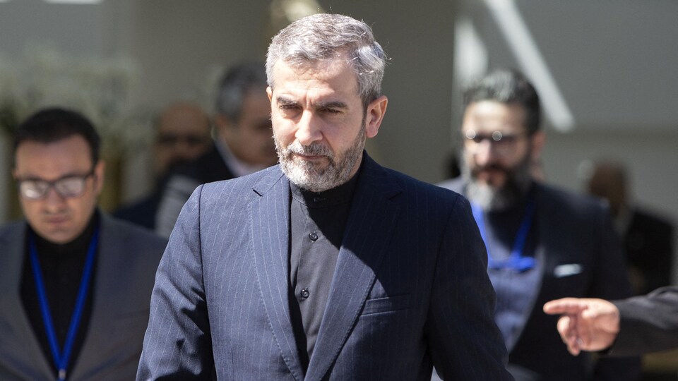 Ali Bagheri Kani marche avec des gens en derrière lui.
