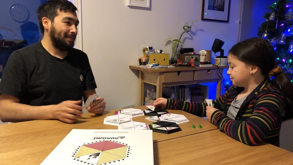 Un père et sa fille jouent à un jeu de société dans le salon.