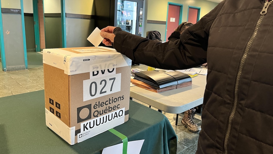 Une électrice de la circonscription d'Ungava dépose son bulletin de vote dans une urne, à Kuujjuaq, le 3 octobre 2022.