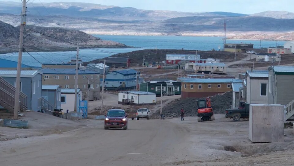 Un village près de l'eau avec des collines derrière.