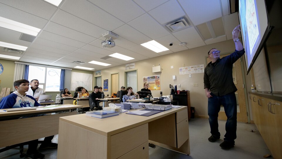 Un enseignant pointe montre une carte projetée sur une toile à ses étudiants, dans une salle de classe du Collège de l'Arctique du Nunavut, en octobre 2022.