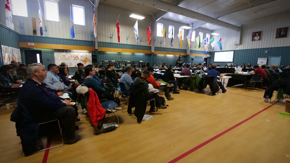Un groupe de personnes assises dans un gymnase durant des consultations publiques, le 14 novembre 2022, à Iqaluit.