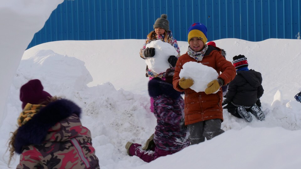 Des enfants transportent des blocs de neige.