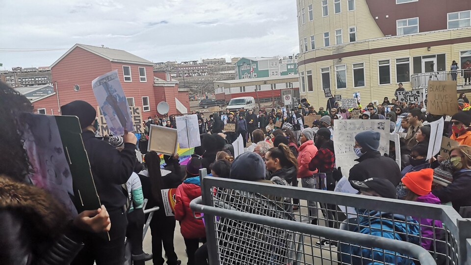 Un groupe de manifestants sont réunis dans une rue d'Iqaluit avec des pancartes.