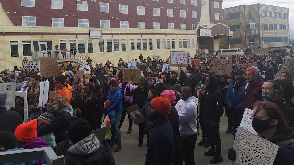 Des manifestants brandissent des affiches sur une place publique d'Iqaluit.