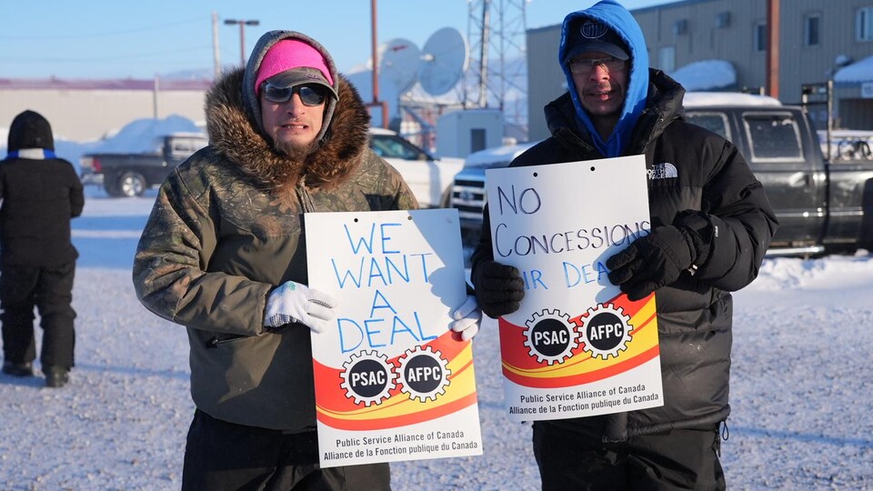 Deux personnes brandissent des pancartes dans une rue enneigée d'Iqaluit, le 17 mars. 