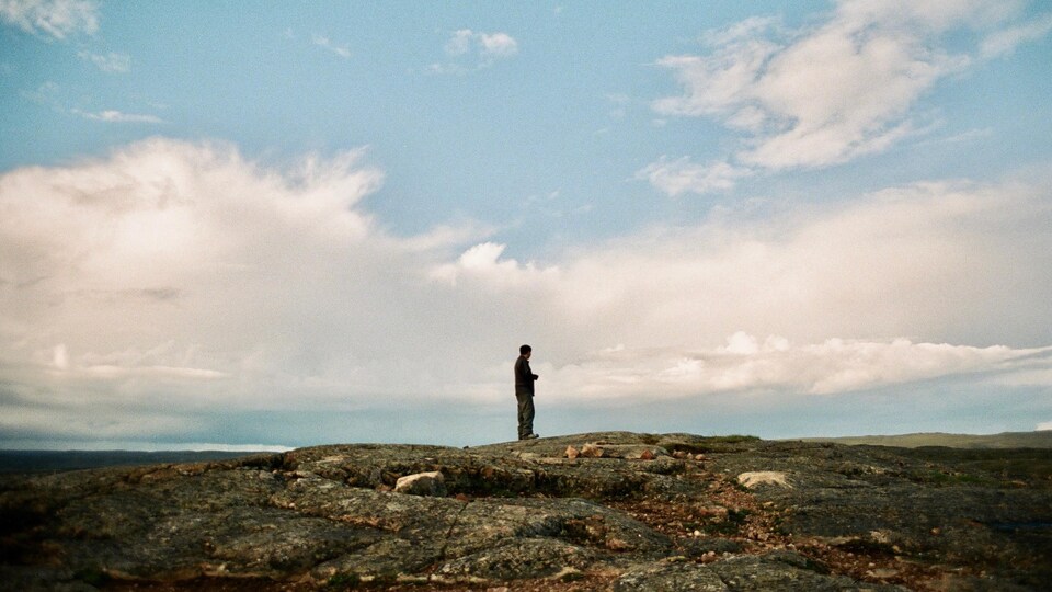 Un homme regarde à l'horizon, dans la toundra.