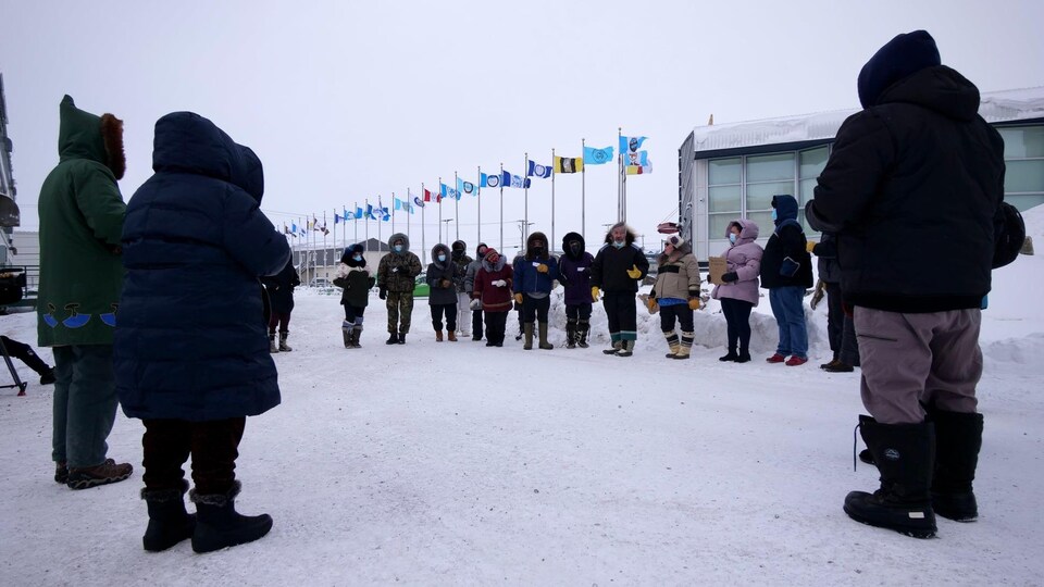 Une vingtaine de personnes sont rassemblées près de l’Assemblée législative du Nunavut lors d'une manifestation silencieuse.