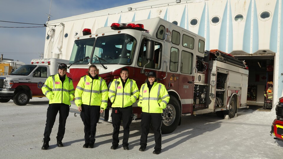 Quatre femmes se tiennent devant un camion de pompiers.