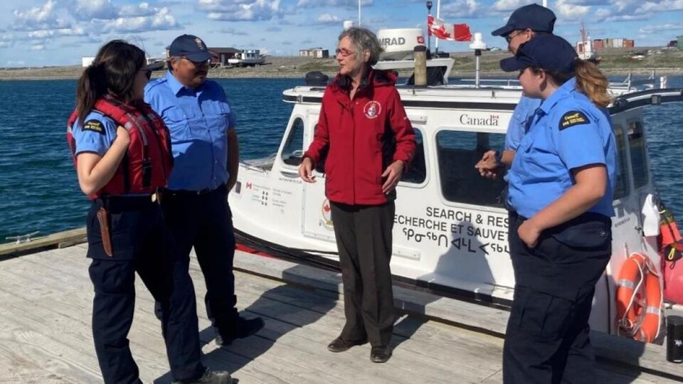 La ministre se tient sur un quai et discute avec quatre membres de la Garde cotière canadienne, à Rankin Inlet, le 10 août 2022.