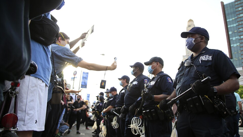 Des policiers masqués du NYPD font face à des manifestants.