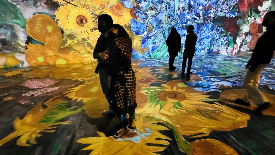 Des personnes regardent les projections d'œuvres de Van Gogh sur des murs.