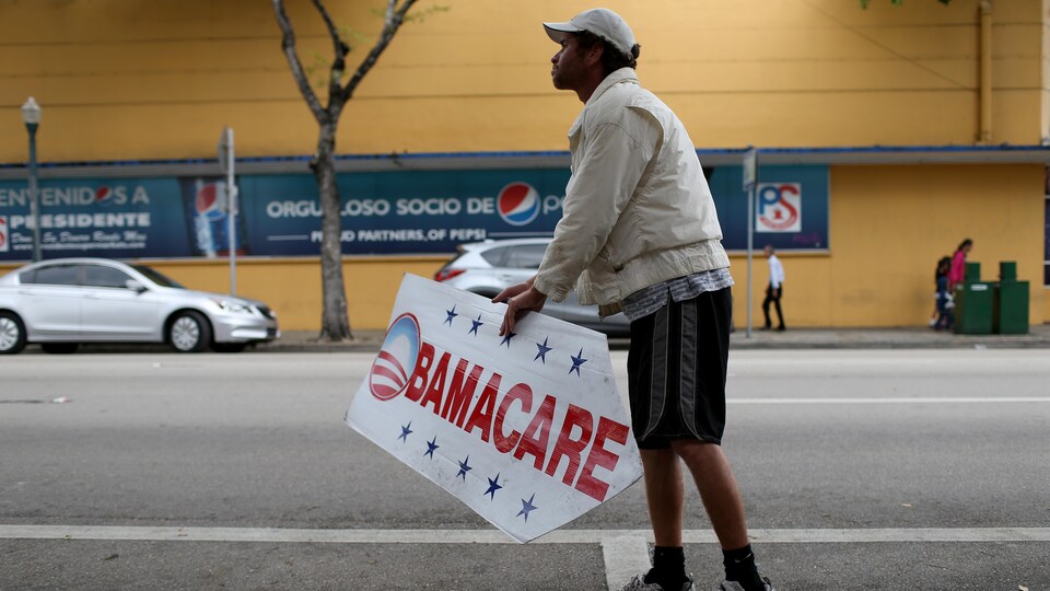 Un homme tient une pancarte invitant la population à s'inscrire à l'Obamacare, le 5 février 2015, à Miami.