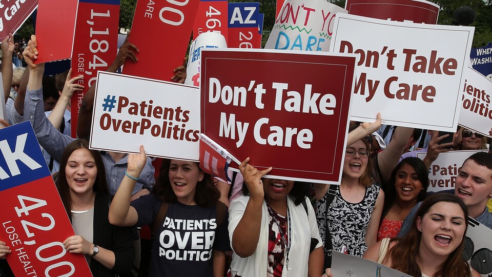 Des jeunes tiennent des pancartes où il est écrit : « Ne prenez pas mes soins de santé ».