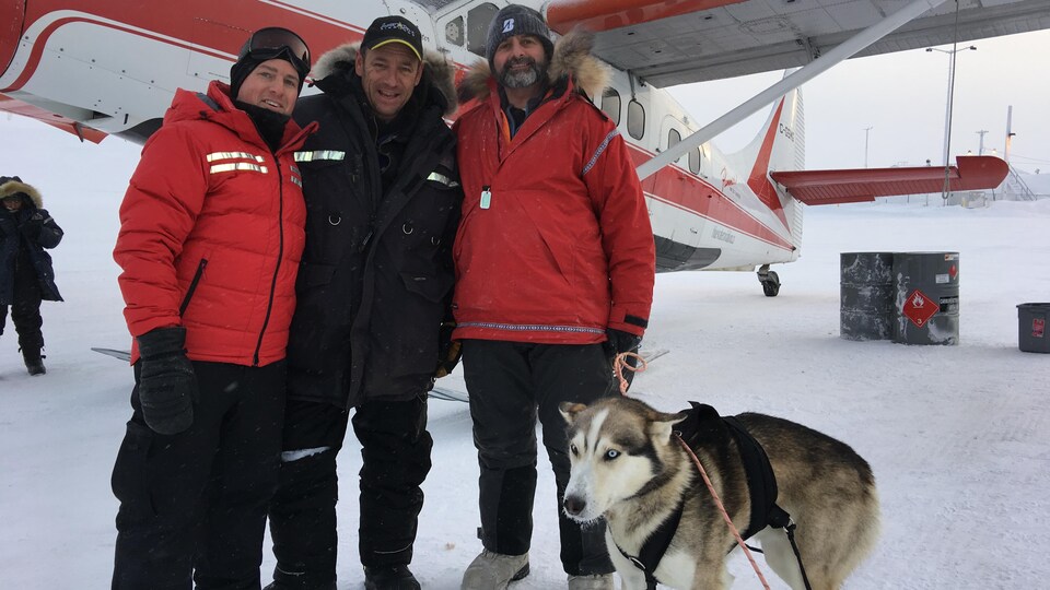 Photo des personnes et du chien devant l'avion sur la glace