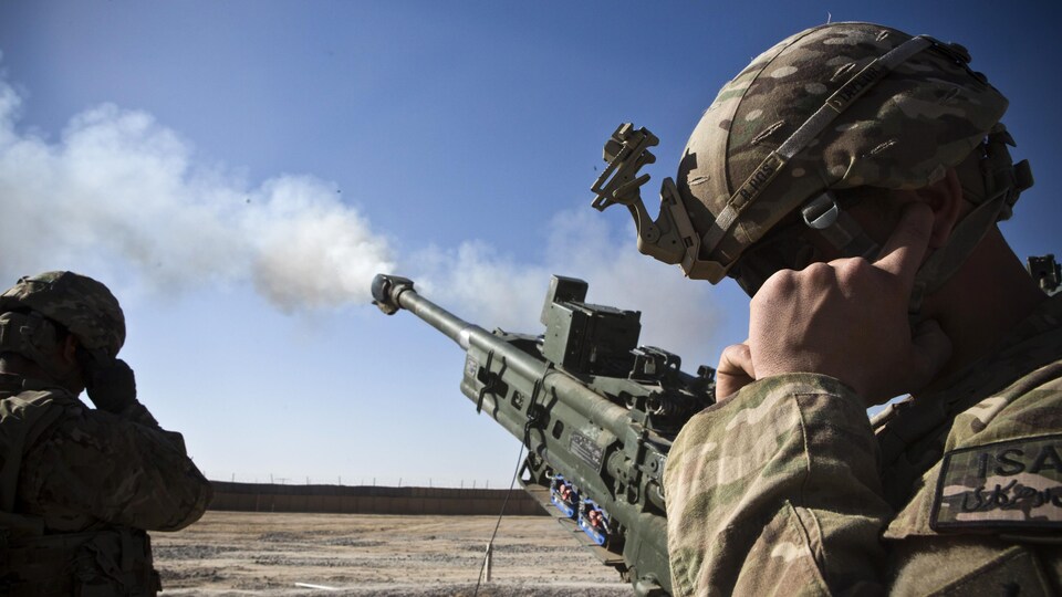 Un soldat se bouche les oreilles lors d'un tir de canon.