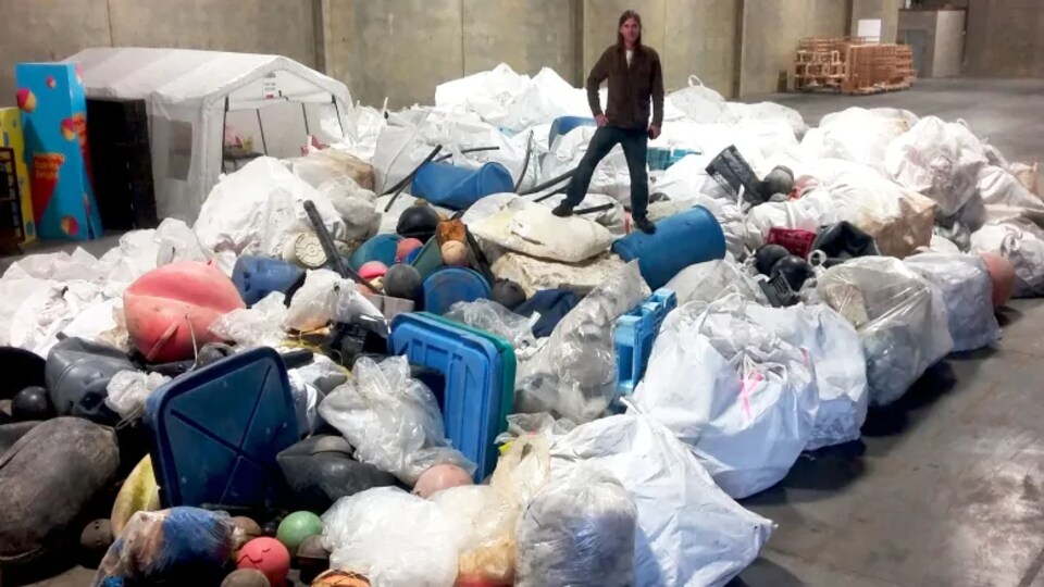 Un bénévole se tient sur un tas de déchets marins.