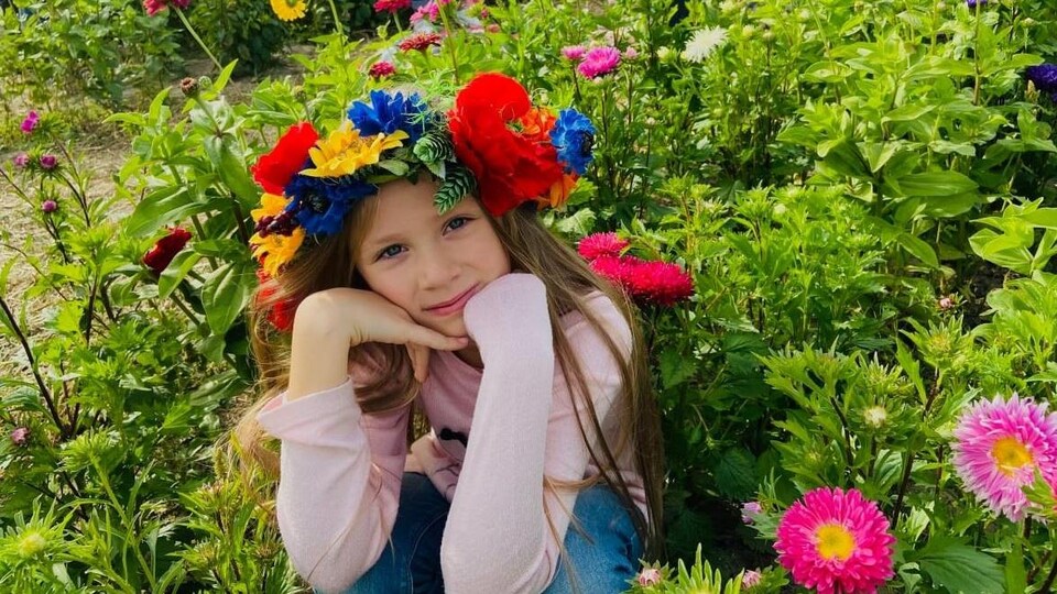 Une petite fille pose au milieu d'un jardin de fleurs. 