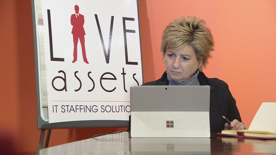 Une femme assise devant une tablette et une pancarte d'entreprise.
