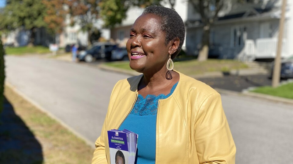 Une femme noire a des dépliants de son programme électoral dans les mains. 