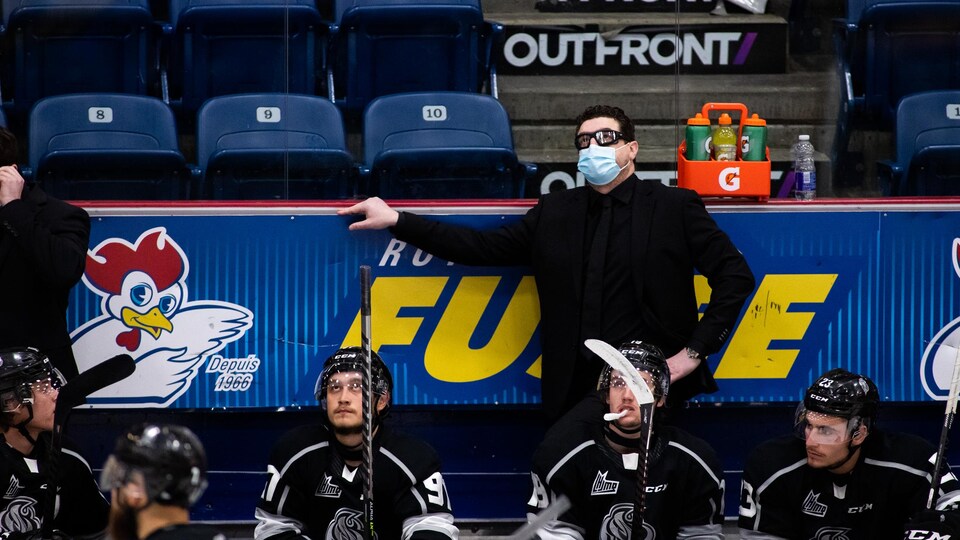 Un entraîneur de hockey regarde l'écran géant pendant un match.