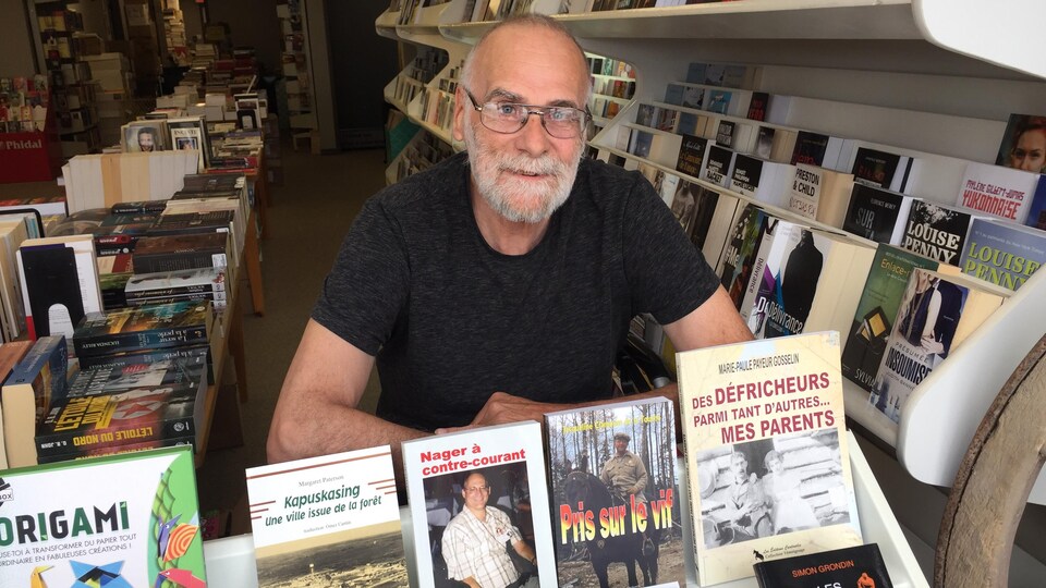 Un homme derrière une table de livres.