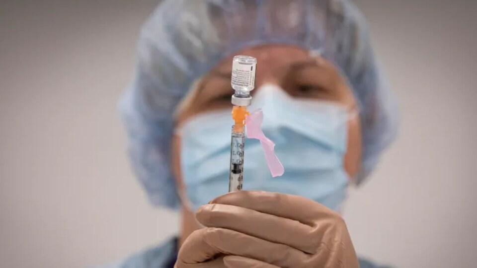 Une infirmière tient une dose de vaccin dans ses mains.