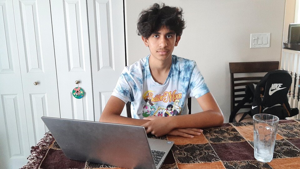 Rayan à la table avec son ordinateur portable devant lui.