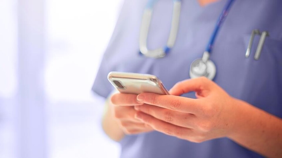 Une infirmière manipulant son téléphone portable.