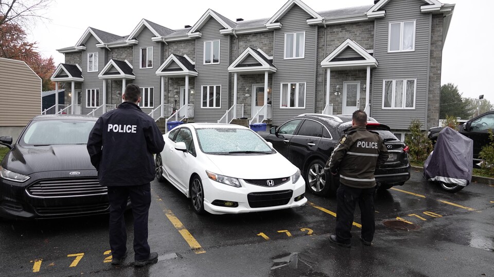 Des policiers montent la garde autour de maisons en rangée.