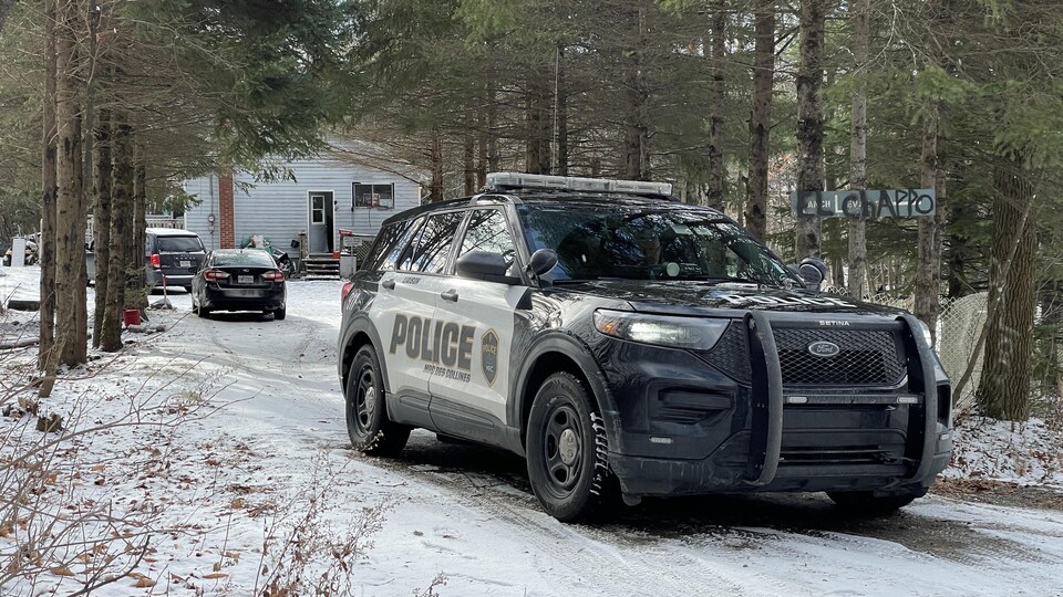 Une voiture de police dans un chemin, en hiver.