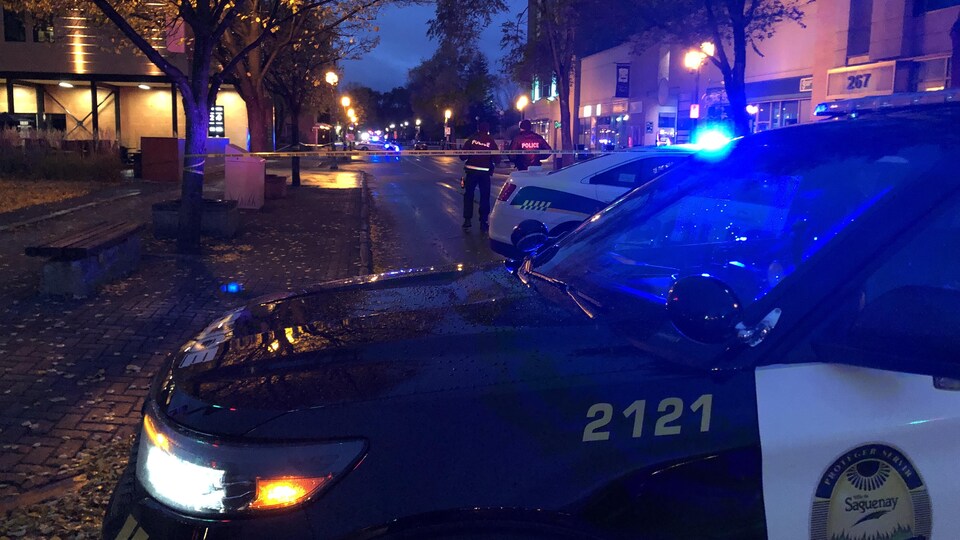 Une voiture de police devant le ruban qui délimite le périmètre de sécurité.