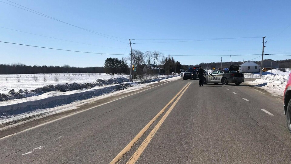 Deux voitures de police sont arrêtées au milieu de la route.