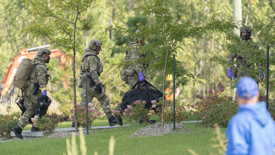 Des agents en tenue de camouflage transportent de l'équipement.