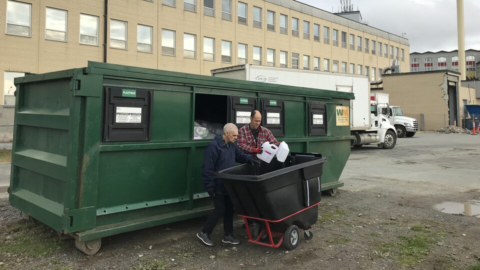 Alain et Richard devant un conteneur à l'arrière de l'hôpital.