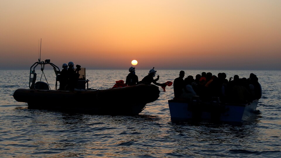 Un bateau de sauvetage aborde un bateau de migrants.